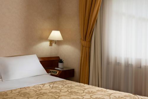 a bedroom with a bed and a lamp and a window at Grand Hotel San Marino in San Marino