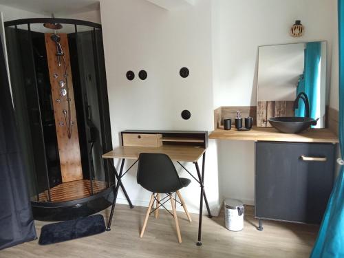 Cette chambre comprend un bureau, un lavabo et un miroir. dans l'établissement La Céliane- climatisé avec patio classé 3 étoiles, à Castelnaudary