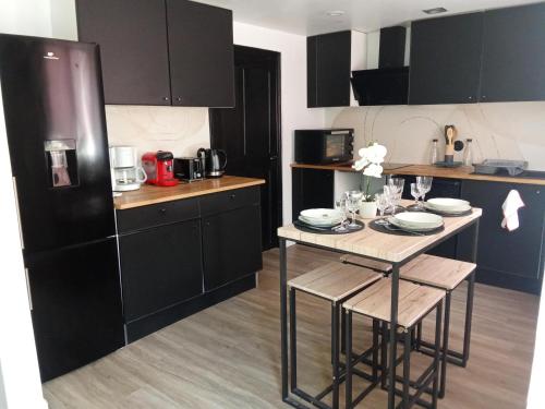 une cuisine avec une table avec des chaises et un réfrigérateur dans l'établissement La Céliane- climatisé avec patio classé 3 étoiles, à Castelnaudary