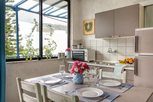 a kitchen with a table with plates and flowers on it at Blue Cactus village center in Agia Pelagia