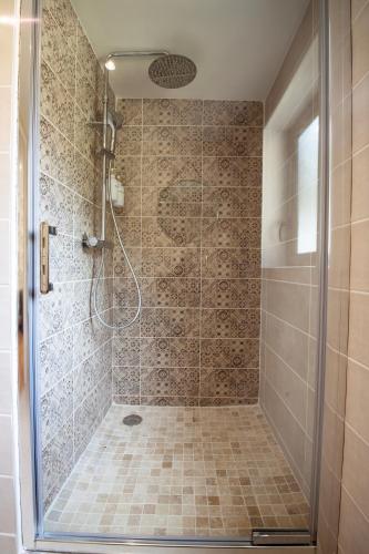 une salle de bain avec une douche avec une porte vitrée dans l'établissement Ô Jacuzzi du Mazet, à Murles