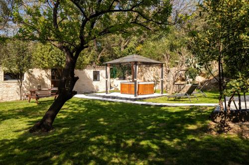 a gazebo and a bench in a yard at Ô Jacuzzi du Mazet in Murles
