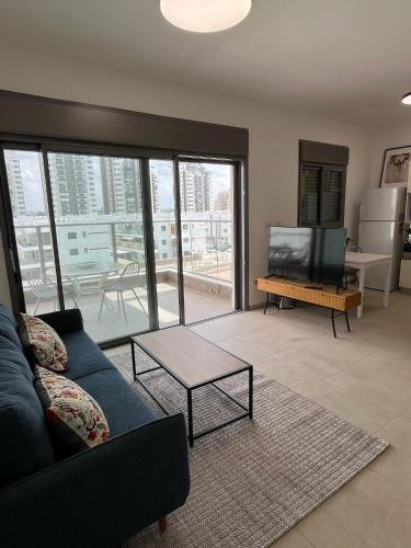 Una sala de estar con un sofá azul y un televisor. en K Home כרמי גת, en Qiryat Gat
