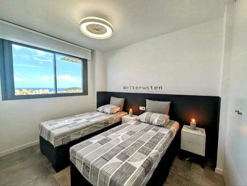 two beds in a room with a window at Seascape Luxury Finestrat in Finestrat