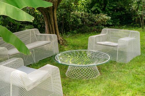a group of wicker chairs and a table in the grass at Gritti Palace Morcote - Waterfront studio with panoramic lake views - Fiordaliso in Morcote