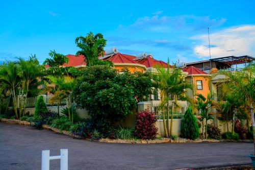 a large yellow house with a fence and trees at Quality Inn Hotel Kigali in Kigali