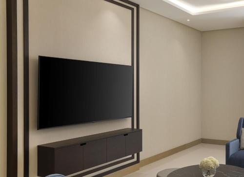 a living room with a flat screen tv on a wall at Hilton Bahrain City Centre Hotel & Residences in Manama
