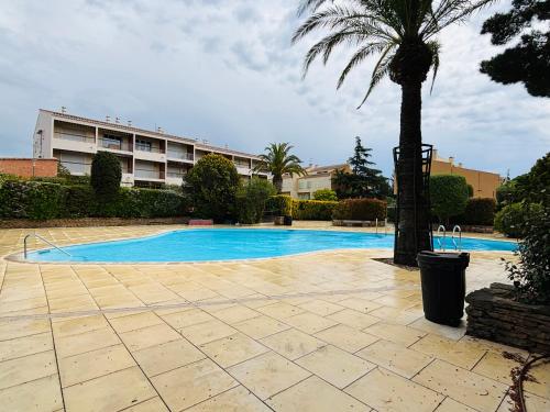 une piscine avec un palmier et un bâtiment dans l'établissement Appartement cosy dans résidence avec piscine et à 2 pas de la mer, à Bandol