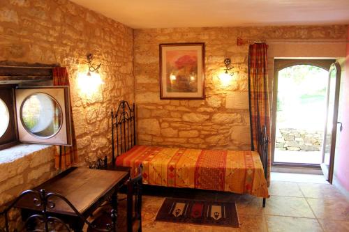 a bedroom with a bed and a table and a window at Domaine du Fraysse Le Cèdre un havre de paix in Saint-Cybranet