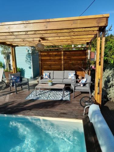 a patio with a couch and a table next to a pool at La case d'Édith in Le Tampon