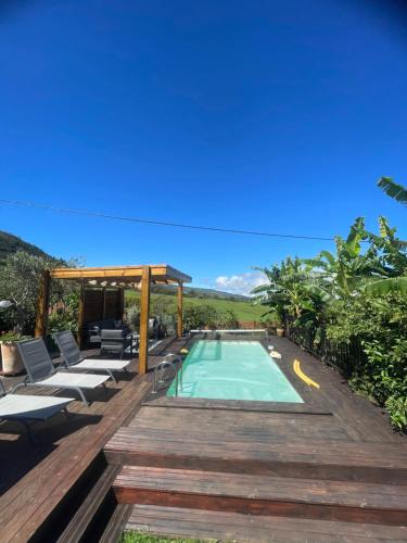 a swimming pool on a wooden deck with chairs at La case d'Édith in Le Tampon