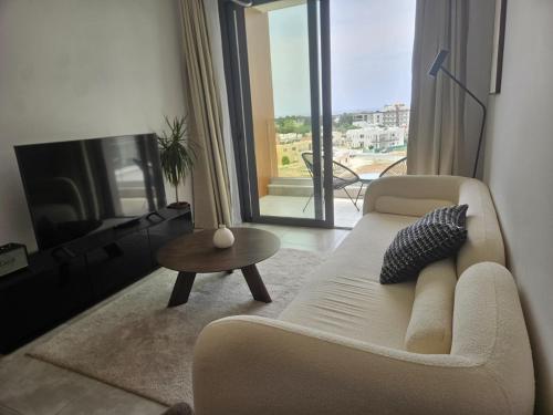 a living room with a couch and a tv and a table at Sea view Penthouse Universal Residences in Nea Paphos