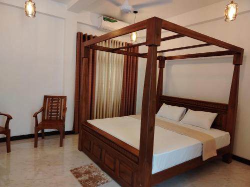 a bedroom with a canopy bed and a chair at Diora Hotel in Ratnapura