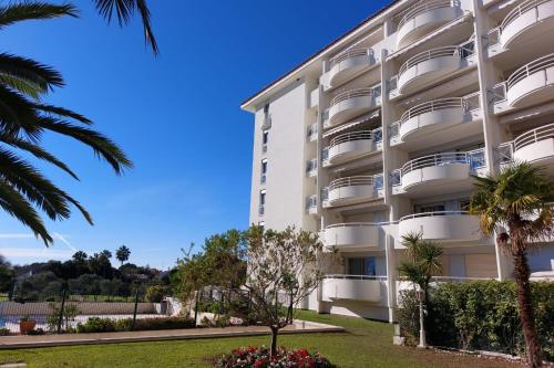 un bâtiment blanc avec des palmiers devant dans l'établissement Cosy seaside apartment with a pool, à Antibes