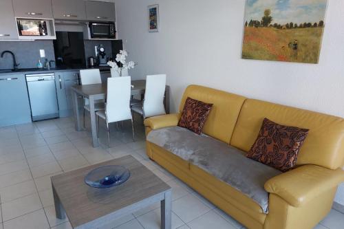 un salon avec un canapé jaune et une table dans l'établissement Cosy seaside apartment with a pool, à Antibes