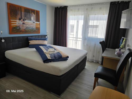 a bedroom with a bed and a desk and a chair at Hotel Ackermann in Riedstadt