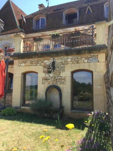 kamienny dom z balkonem i oknami w obiekcie Domaine du Fraysse Le Cèdre un havre de paix w mieście Saint-Cybranet