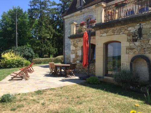 a patio with a table and chairs next to a building at Domaine du Fraysse Le Cèdre un havre de paix in Saint-Cybranet