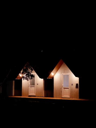 a wooden building with two doors at night at Maravillosso Sathram in Vandiperiyār