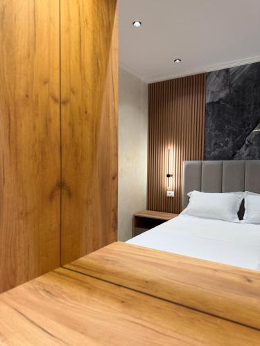 a bedroom with a bed and a wooden wall at Kamberi Hotel & Apartments in Velipojë