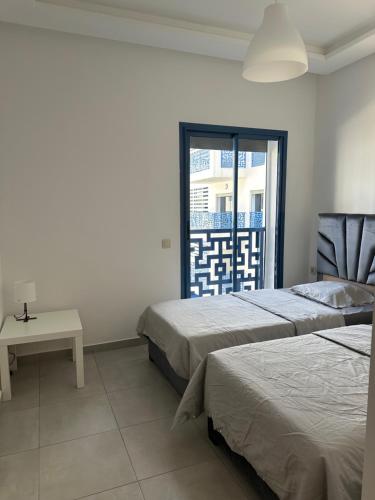 a bedroom with two beds and a table and a window at BLANCO 2 Costa MAR MARTIL in Martil