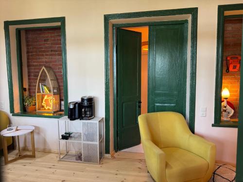 a room with a yellow chair and a green door at Our Old House in Tʼelavi