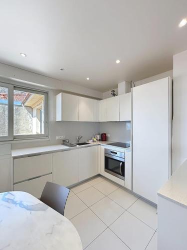 une cuisine avec des armoires blanches et une table dans l'établissement Cannes Suquet stunning sea view bright apartment prime quiet location, à Cannes