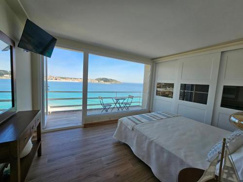 a bedroom with a bed and a view of the ocean at Casa Peñascales -Laxe- Costa da Morte in Laxe