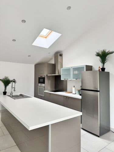 La cuisine est équipée d'un comptoir blanc et d'un réfrigérateur. dans l'établissement maison Mila, à Gardanne