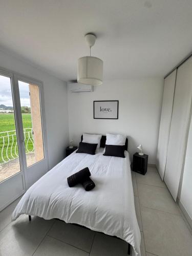 une chambre blanche avec un grand lit et une fenêtre dans l'établissement maison Mila, à Gardanne