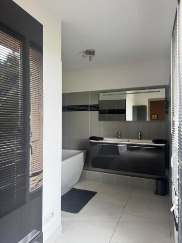 une salle de bain avec une baignoire, un lavabo et un miroir dans l'établissement maison Mila, à Gardanne