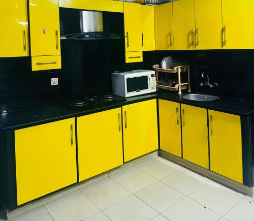 cocina amarilla con armarios amarillos y microondas en Luxury apartment at bahria town, en Rawalpindi