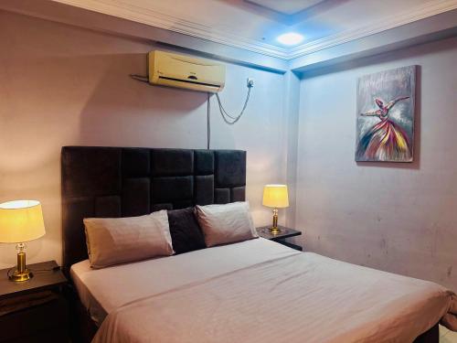 Un dormitorio con una cama y dos lámparas y un cuadro. en Luxury apartment at bahria town, en Rawalpindi