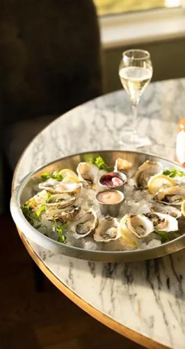 a bowl of oysters on a table with a glass of wine at Butler Arms Hotel in Waterville