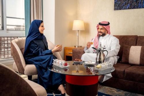 a man and a woman sitting in a living room at Tulip Inn Al Daar Rawafid in Al Madinah
