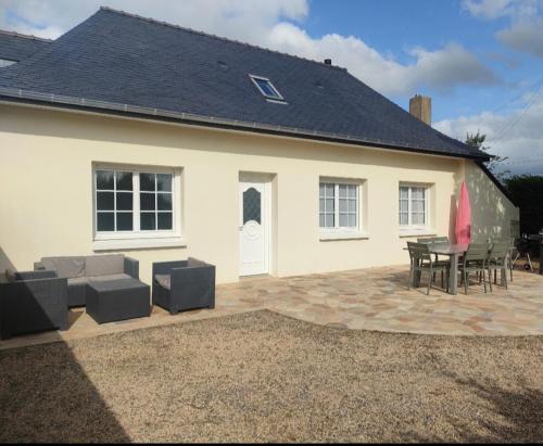 Cette maison blanche dispose d'une terrasse, d'une table et de chaises. dans l'établissement Maison de campagne, à Sceaux-dʼanjou
