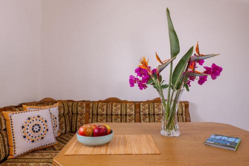 a table with a vase of flowers and a bowl of fruit at Elpis House in Nydri