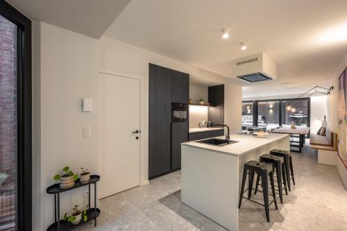 a kitchen with a white counter and stools at Borgraaf - Palazzio in Borgloon