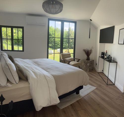 une chambre blanche avec un grand lit et une chaise dans l'établissement L'Écrin de la Sapinière, à Merville