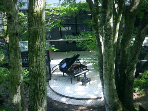 a black piano sitting in a park between two trees at クリエイティブな人の遊び場!最大16名リンカンスタジオRINKAN Studio in Ito