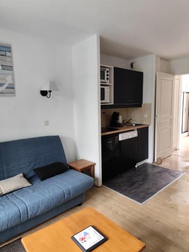 un salon avec un canapé bleu et une cuisine dans l'établissement Chez l'Amiral Alain, à Marciac