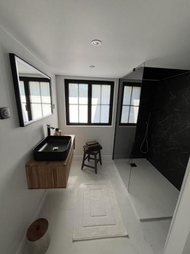 La salle de bains est pourvue d'une baignoire noire et d'un lavabo. dans l'établissement L'Écrin de la Sapinière, à Merville