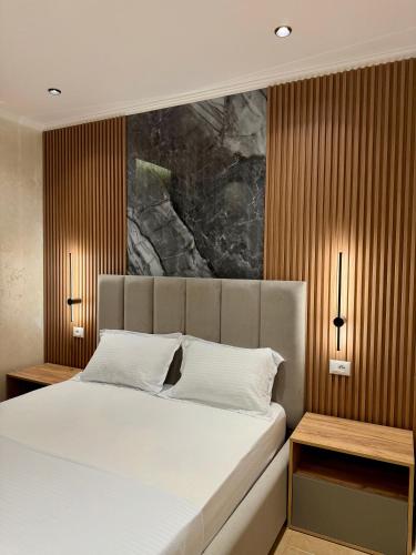 a bedroom with a large white bed with two tables at Kamberi Hotel & Apartments in Velipojë
