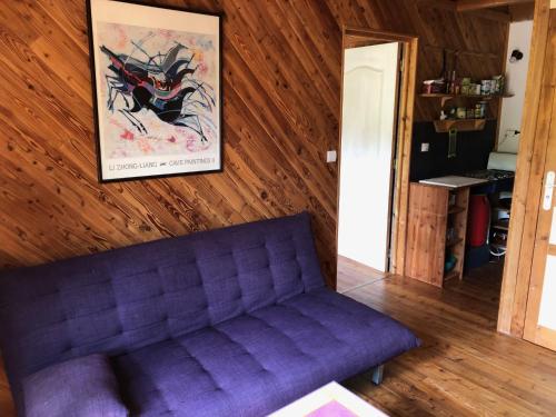 - un canapé violet dans le salon avec une photo sur le mur dans l'établissement Les Abeilles, à Eymoutiers