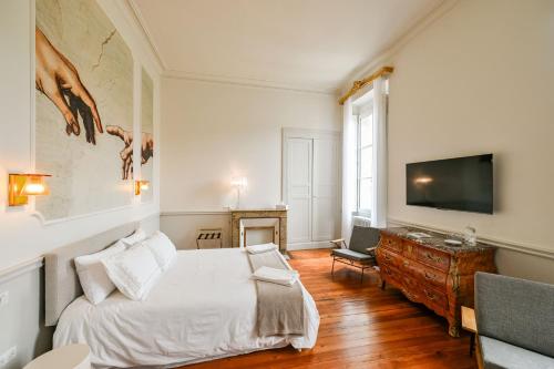 une chambre avec un lit et une télévision à écran plat dans l'établissement DE L'ART À LA MANIÈRE - Chambre d'Hôtes de Charme - 2 Suites Haut de Gamme - Idéal Couple & Famille - Piscine - Terrasse - Calme - 15min Saint-Émilion - EXPÉRIENCE Restauration d'Oeuvre d'Art, à Branne
