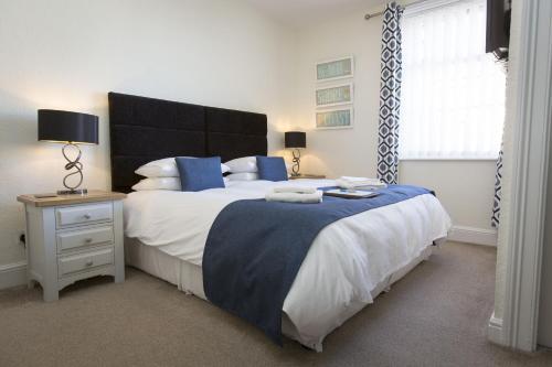 a bedroom with a large bed with blue pillows and a window at Rosslyn House in Whitby