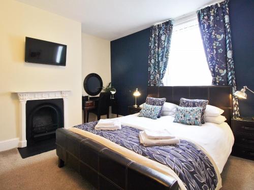 a bedroom with a large bed with a fireplace at Rosslyn House in Whitby