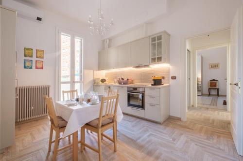 a kitchen with a table and chairs and a kitchen with white cabinets at Brand New !!! Ancient BOLOGNA Centrale LIBERTY Style Completely RENOVATED 2025 in Bologna