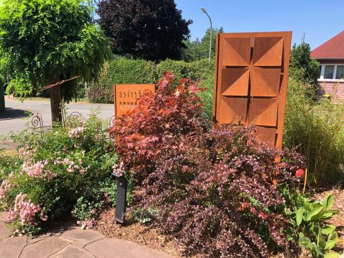 a garden with flowers in front of a sign at Ferienwohnung Haus Angela in Güdesweiler