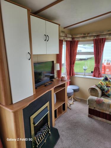 a living room with a fireplace and a tv at Home from home in Little Holland